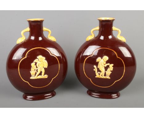 A pair of brown glazed moon flask vases with Pate-Sur-Pate decoration depicting cherubs, with mustard interior. Height: 23cm.