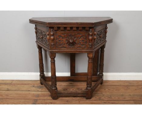 An oak carved credence fold over side table with gate leg to back, strapwork decoration with central drawer flanked by half t