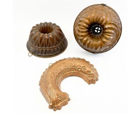 Three copper light gauge jelly moulds including circular examples 25.5 cm and 23.5 cm, and another in the form of a fish 29.5