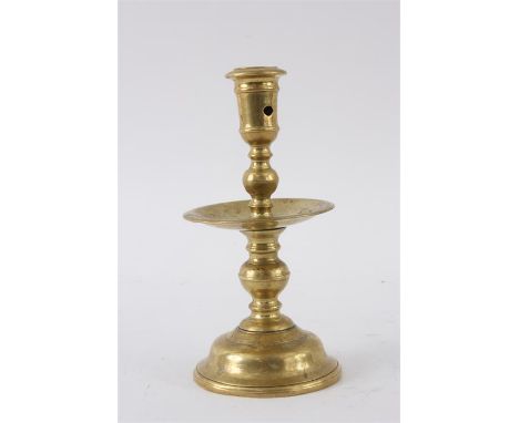 A 17TH CENTURY CAST BRASS HEIMSKIRK CANDLESTICK with domed spun base, double knopped stem and centre drip tray; with a pierce