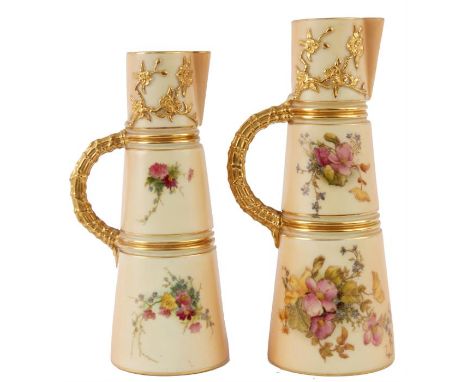 TWO ROYAL WORCESTER GRADUATED GILT-EDGED TAPERING BLUSHED IVORY CLARET JUGS with ringed bodies and bamboo handles decorated c