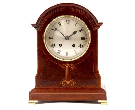 AN EDWARDIAN MARQUETRY INLAID MAHOGANY ARCH-TOP MANTEL CLOCK with plinth base and brass ogee feet, the silvered convex dial w