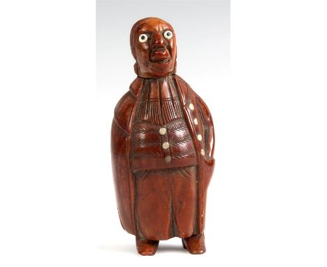 A LATE 18TH CENTURY CARVED FIGURAL COQUILLA NUT SNUFF BOX of a man wearing a long cape with bone buttons and hinged lid to th