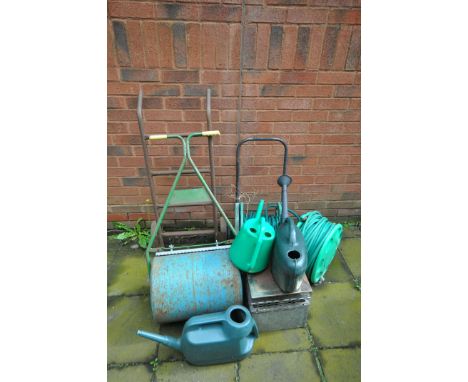 A SELECTION OF GARDEN ITEMS, to include a roller, two hose pipes and reels, three watering cans, chimney topper, along with a