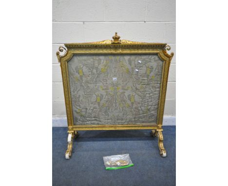 A 19TH CENTURY GILT FRAMED FIRE SCREEN, with crown on a cushion pediment, foliate scrolls, surrounding a glass panel protecti