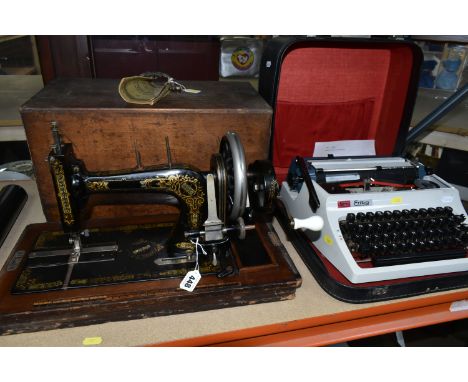 A VINTAGE SEWING MACHINE AND TYPEWRITER, comprising a cased hand cranked sewing machine, the case and base of the machine wit