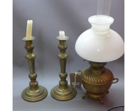 A pair of brass candlesticks together with a Victorian brass oil lamp having opaque glass shade, and a copper cooking pot