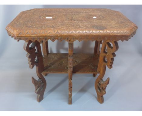 A carved wood table possibly Burmese, carved with birds and foliage. A shelf below and ornate carved legs