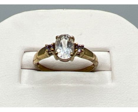 Ladies 9ct gold ring. Set with oval cz in centre and small pink/purple stone set either side. 1.9g size K