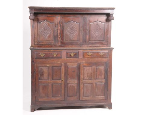 A 17th Century style oak court cupboardThe upper part with three fielded panelled doors each centred with a carved lozenge an