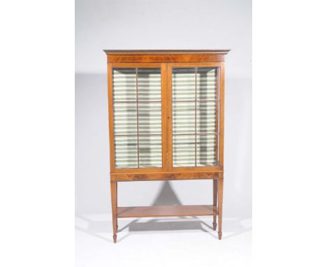 An Edwardian inlaid mahogany display cabinetWith a moulded cornice above a frieze inlaid with stringing, over a pair of astra