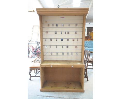 A modern pine shop display unitWith an over hanging canopy above an arrangement of metal hanging fittings and a shelf with tw