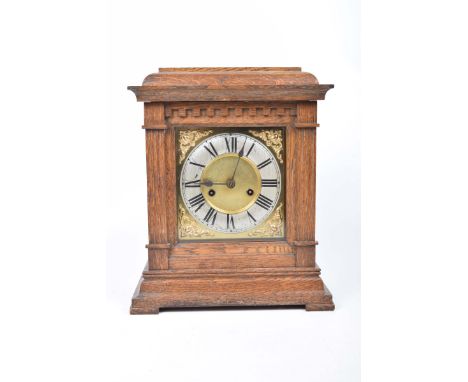 An early 20th Century oak cased bracket clockThe case with a caddy top above two fluted columns flanking a gilt metal dial wi