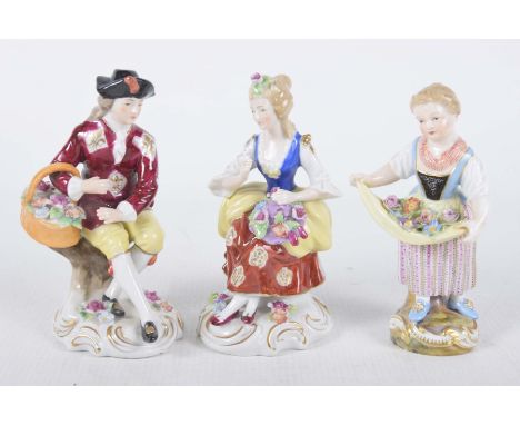 Three late 19th early 20th Century Continental figuresTo include a flower seller perched on a branch wearing a black hat, a l
