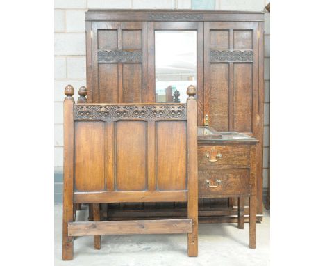 An early 20th Century oak bedroom suiteComprising a double wardrobe with a caddy top above a central mirrored panel flanked b