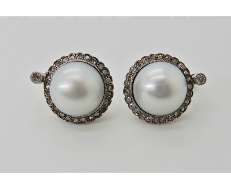 A pair of pearl and diamond earrings, with white metal continental post and clip fastening pearls are slightly 'button' in sh