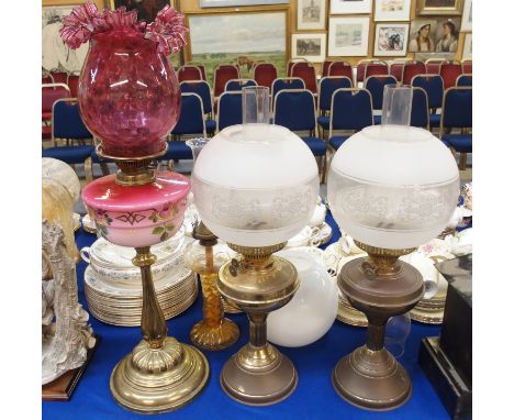 A brass paraffin lamp, with cranberry glass reservoir and shade, a pair of brass paraffin lamps, another lamp, white glass sh