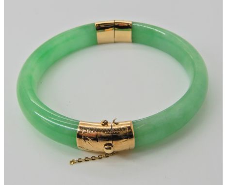 A 14k gold mounted Chinese green hardstone bangle, weight approx 44gms  Condition Report: 