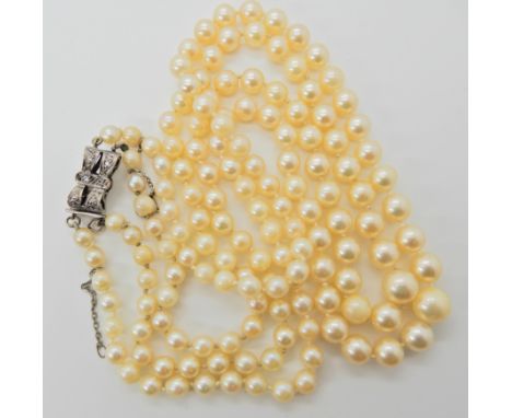 A double string of cultured pearls with a white metal clear gem set bow clasp with safety clasp length of shortest strand 50c