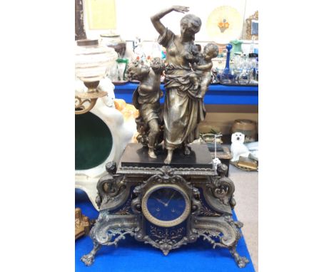 A large spelter figural mantel clock, the base inset with black slate and gilt decorated panels, the whole surmounted with a 