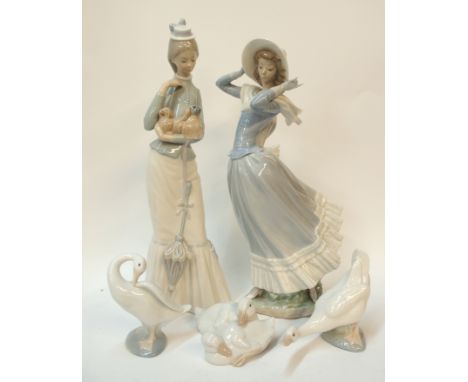 Two Lladro figures including one of a lady holding a Pekinese, the other of a lady holding onto her hat, together with Lladro