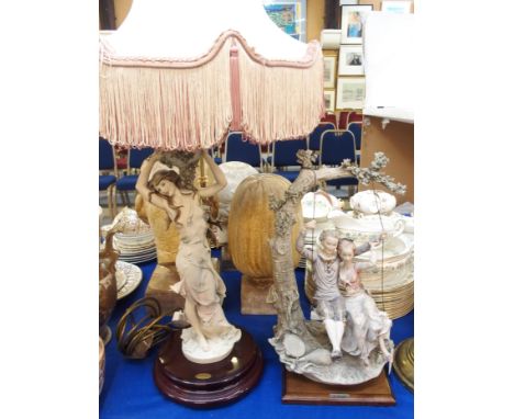 A Guiseppe Armani Florence figural table lamp, modelled as a woman holding an urn, together with a figure of a couple on a sw