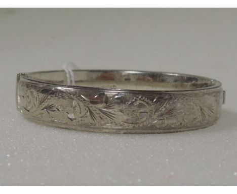 An HM silver hinged bangle having engraved decoration and slide clasp