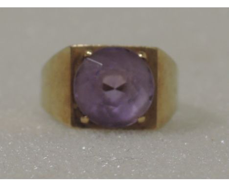 A ladies dress ring  having an amethyst stone in a stylised setting on a heavy 9ct gold loop