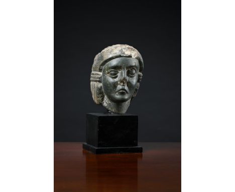 AN EARLY CARVED GREEN BASALT HEAD  POSSIBLY LEVANTINE OR PALMYRENE, CIRCA 100-300 A.D  Remnants of headdress flanking face, l