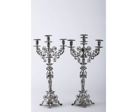 A pair of four-light candelabra, 833/1000 silver, decoration and stems en relief "Female figures holding pitchers", zoomorphi