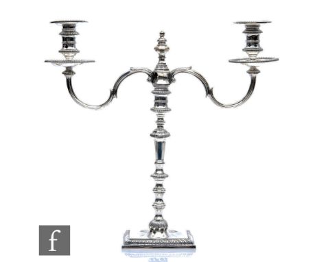 A hallmarked silver twin light cast candelabra, square base with gadroon detail to border below double knopped column twin sc