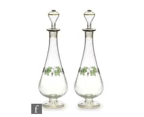 A pair of 1930s Czechoslovakian glass decanters, each of footed tapering form, the clear body enamel decorated with a band of