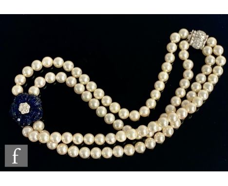 A double row choker of uniform cultured pearls with central seven stone diamond cluster within a sapphire set petal design, t