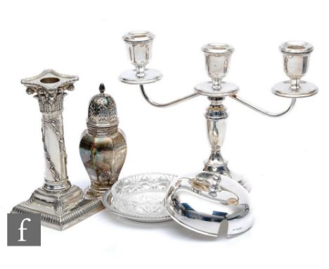 Four items of hallmarked silver, three light squat candelabra, a circular butter dish and cover, a sugar castor and a single 