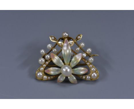 An enamel and seed pearl 15 ct gold floral brooch, singlw large culture pearl within eight petal enamelled setting, surrounde
