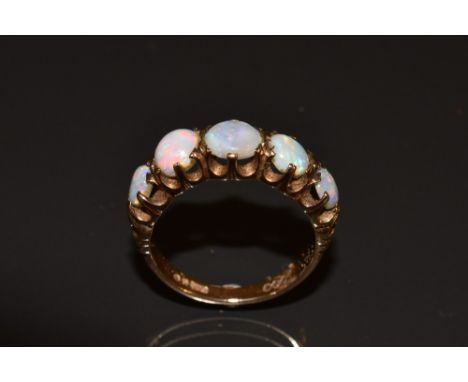 A five stone opal ring, each graduating circular cabochon opal flashing green, orange, red, blue and violet colour play, 9ct 