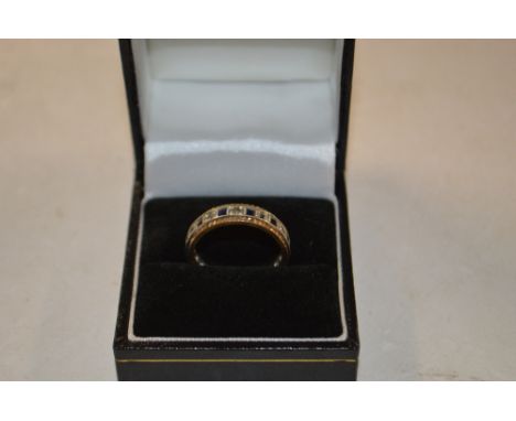 A yellow and white metal eternity ring set with blue and white stones