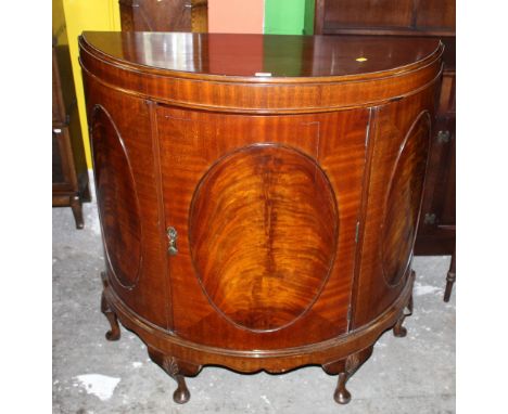 A 1920's flame mahogany bow fronted pier cabinet the top with quartered matched veneer, fitted single shelf enclosed by oval 