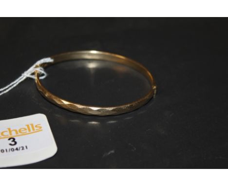 A 9ct rolled gold bangle of faceted design, marked 9ct R.G.,  6.5 cm wide