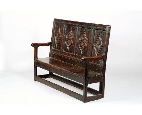 Early 18th Century carved oak bench, four carved panel back decorated with a geometric design, raised on block legs united by