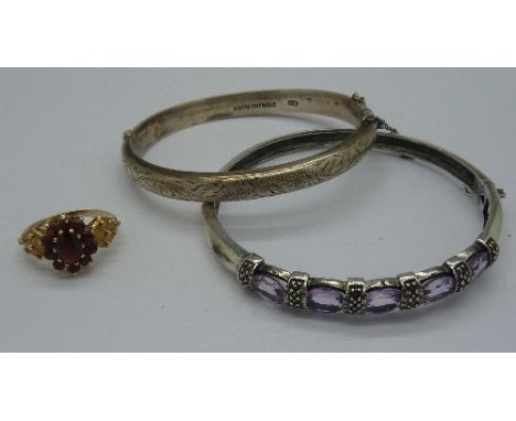 A 9ct gold and garnet cluster ring, a silver and amethyst bangle and another silver bangle, weight of ring 3.2g, size N