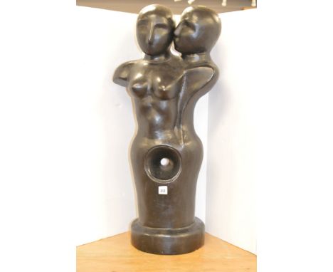 A modern black painted model of an embracing couple, 77cms high.