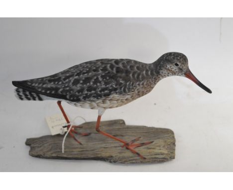 A carved model of a redshank on a driftwood plinth.