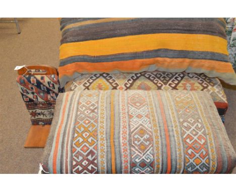 Two ottomans; together with a large scatter cushion; and a further item, all upholstered in Middle Eastern carpet.