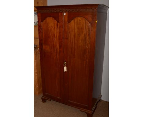 A late 19th Century gent's mahogany wardrobe, the panelled doors opening to reveal hanging space, raised on bracket feet, 164