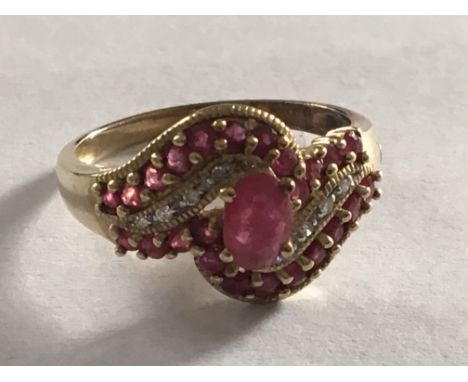 A 9carat yellow gold ring set with a pattern of ruby coloured stones and small diamonds. Ring size P.