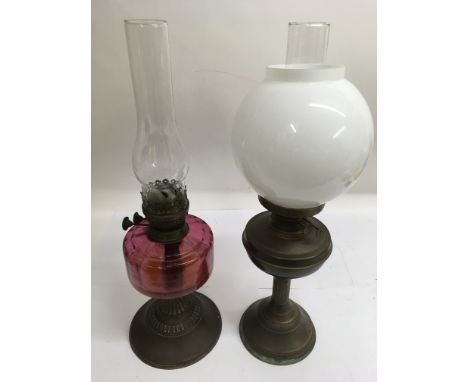 A cranberry glass oil lamp and one other with white shade