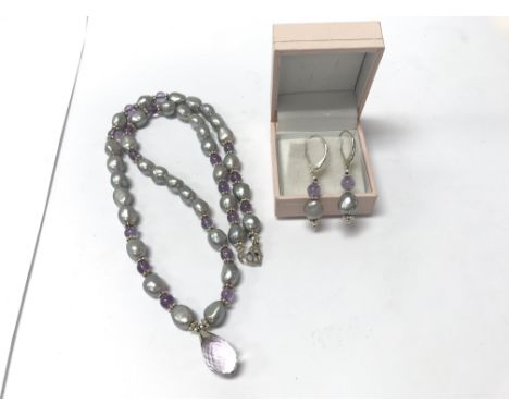 A string of amethyst and pearl necklace with facet ball pendant together with a matching pair of earrings.