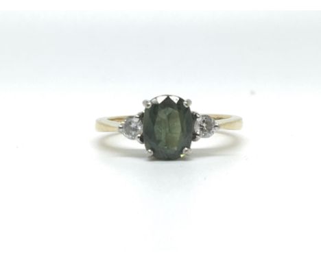 An 18ct yellow gold ring set with a large central green stone flanked by a diamond either side. Total weight approximately 3.