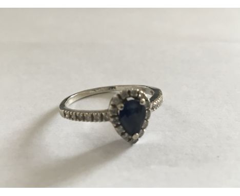 A 14 carat white gold ring set with a blue sapphire flanked by small diamonds. Ring size P.